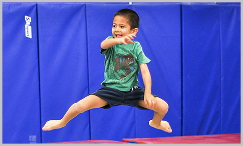 A recreational trampoline student smiles as he jumps on the trampoline during class at AIM Gymnastics' Pickering location.