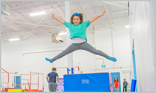 A smiling student jumps off the vault during a birthday party at AIM Gymnastics' Ajax location.