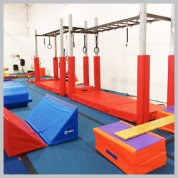 Ninja obstacle course structure at AIM Gymnastics Ajax. Set of rings, slanted mats, and a balance board.