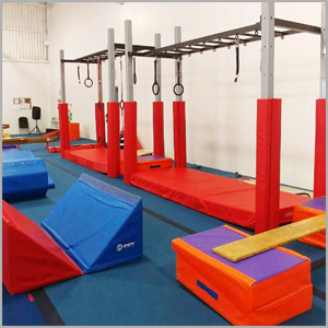 Ninja obstacle course structure at AIM Gymnastics Ajax. Set of rings, slanted mats, and a balance board.